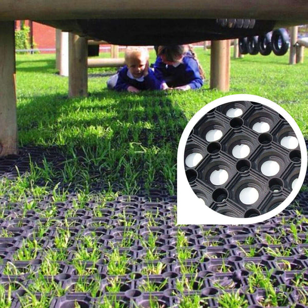 Children playing on heavy-duty rubber grass mat; slip-resistant grid pattern with circular drainage holes provides safety, drainage and impact absorption on playgrounds (BS EN 1177 certified)