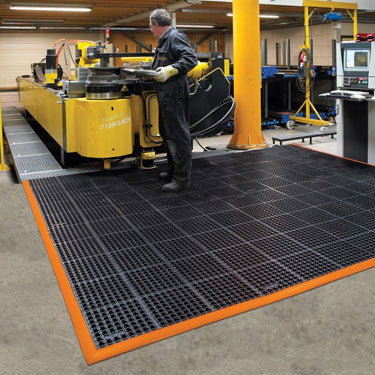 Worker on heavy-duty industrial mat on factory floor