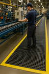 Worker walking on 16mm interlocking rubber link mats with drainage holes; heavy-duty interlocking rubber mats with link-style design and circular drainage holes provide slip-resistant flooring and water drainage in pools, wet areas and industrial environments