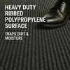 Close-up of heavy-duty ribbed polypropylene entrance mat with polished shoe stepping; grooves trap dirt and moisture and improve traction