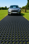 Car parked on heavy‑duty 10 m non‑slip rubber grass mat roll used as driveway mat; black open‑ring design provides traction, drainage and mud control for lawn and driveway.
