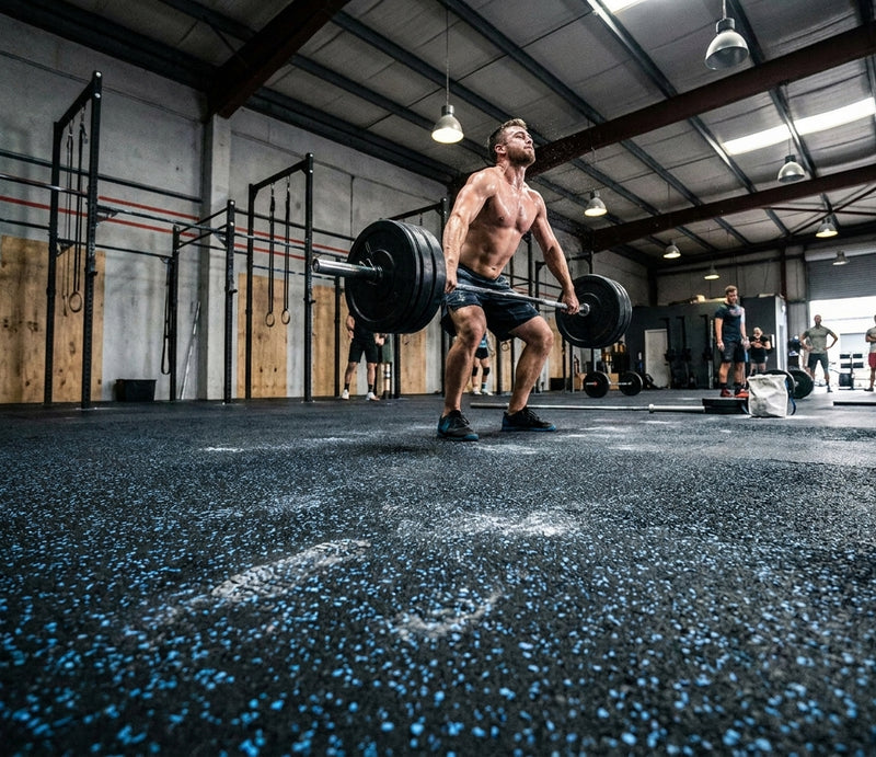 Blue fleck rubber gym matting roll in CrossFit box — black rubber base with blue EPDM flecks, seamless roll floor, Olympic lifting
