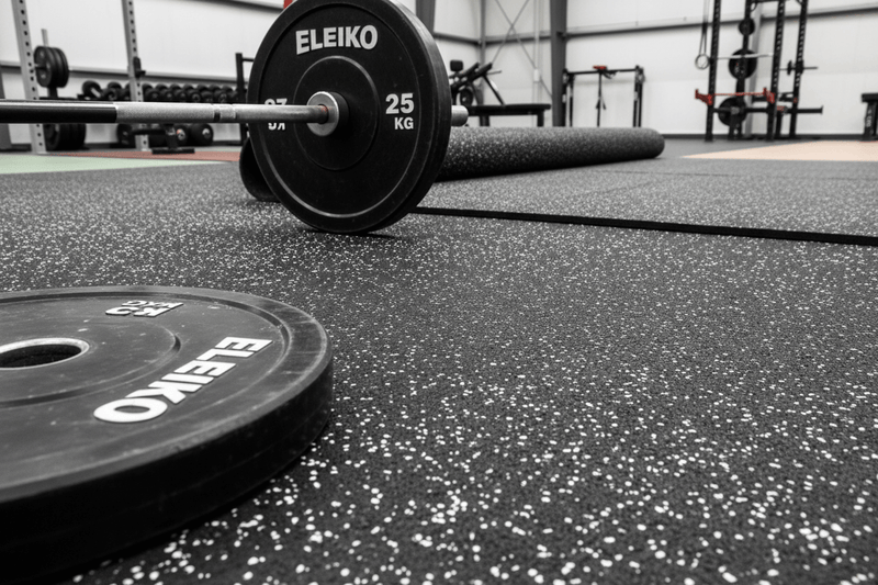 Close-up detail of black rubber gym flooring showing white EPDM fleck pattern