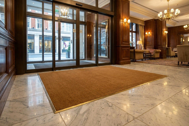 Natural coir matwell installation at luxury hotel lobby — flush-fit entrance matting recessed into marble floor, professional commercial fit