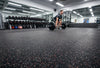 Black rubber gym matting roll installed in commercial weight room — 1.25m x 10m seamless roll, deadlift in progress