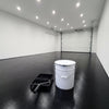 Black floor paint in a modern garage with a white sectional door, 20 litre tin and roller tray