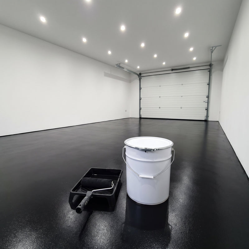 Black floor paint in a modern garage with a white sectional door, 20 litre tin and roller tray