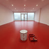 Bright red floor paint in an empty showroom with a frosted glass frontage, 20 litre tin and roller tray