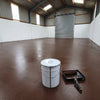 Brown floor paint in a rural workshop barn with a roller shutter door, 20 litre tin and roller