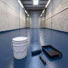 Dark blue floor paint in an engineering workshop with a roller shutter door, 20 litre tin and roller