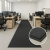 Long heavy-duty non-slip rubber runner in an office workspace with desks and chairs; ribbed texture channels water and dirt; inset shows close-up capturing moisture and improving traction; protects floors and reduces slips in busy workplace.