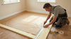 Professional carpet fitter laying 11mm PU foam underlay — paper backing face up, trimming to size, UK home installation