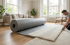 12mm memory foam luxury carpet underlay being laid in UK living room — thick grey PU foam roll, professional installation