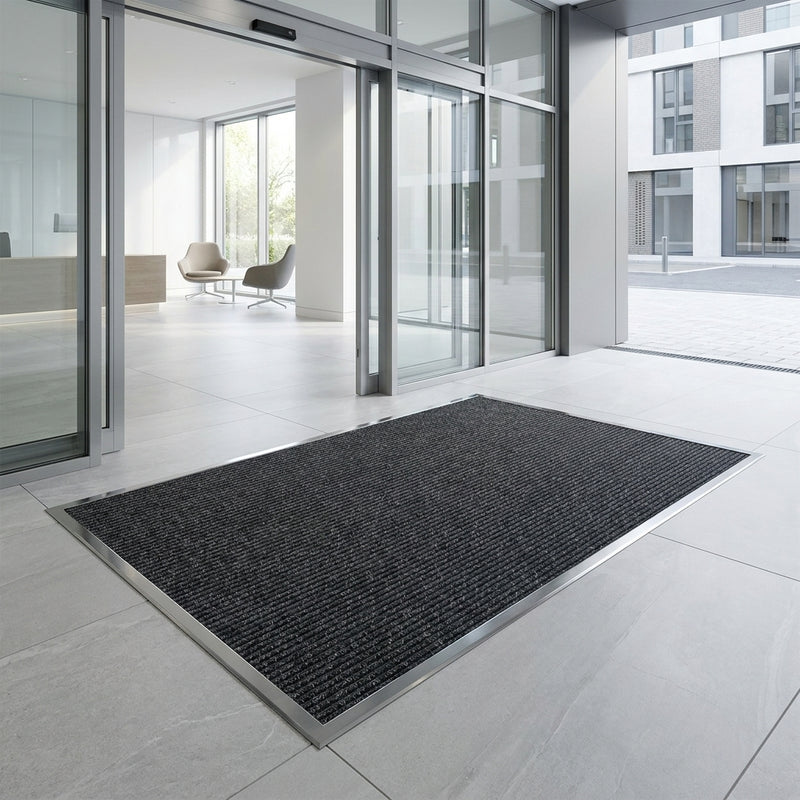 Anthracite polypropylene entrance matting installed flush in matwell — patterned fibre bonded sheet, 10mm thick, commercial building entrance