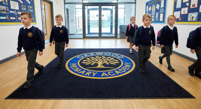Custom school logo mat at academy entrance — vibrant printed school crest and name, heavy duty commercial pile, slip-resistant backing