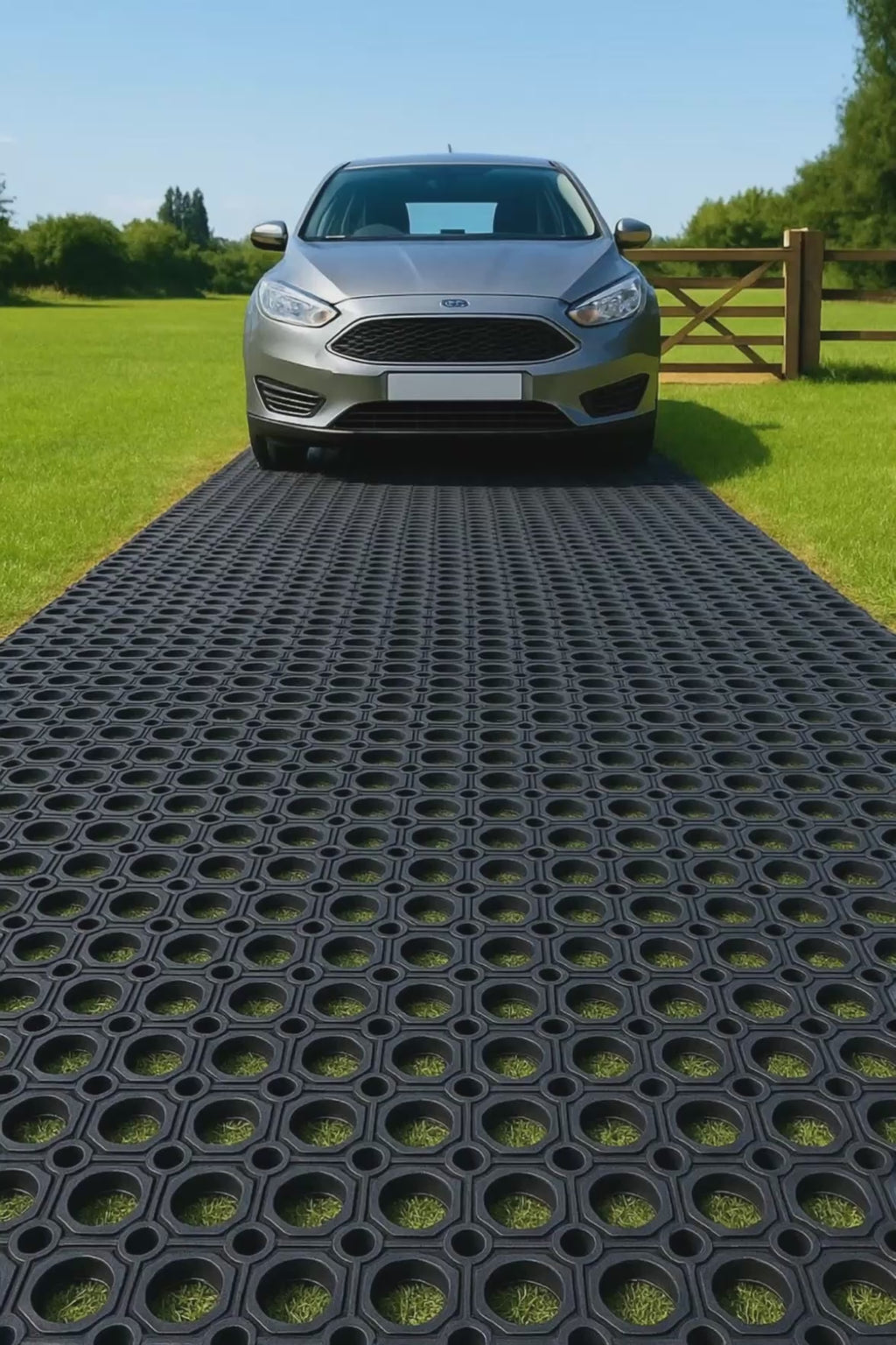Video of a car driving onto a heavy-duty non-slip rubber grass mat laid on a lawn; the open-ring design reinforces the ground, provides traction and drainage, and creates a stable driveway surface while allowing grass growth and preventing mud