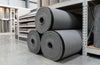 12mm memory foam carpet underlay rolls in trade showroom — thick grey foam with black DPM membrane, 3 sizes available: 5m², 7.5m², 15.07m²