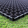 Black rubber grass mats with grid design laid on grass surface for safe playground or lawn walkway