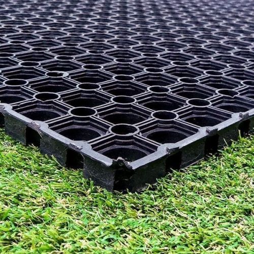 Black rubber grass mats with grid design laid on grass surface for safe playground or lawn walkway