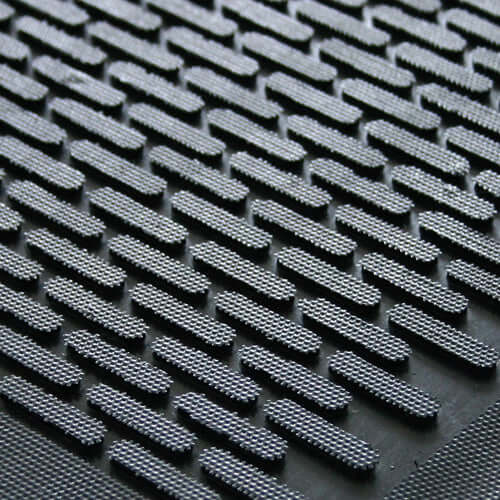Close-up of raised brick pattern on heavy-duty nitrile rubber entrance mat; textured ridges aggressively scrape debris and channel water and oil to trap dirt and moisture, providing non-slip traction for busy outdoor entrances.